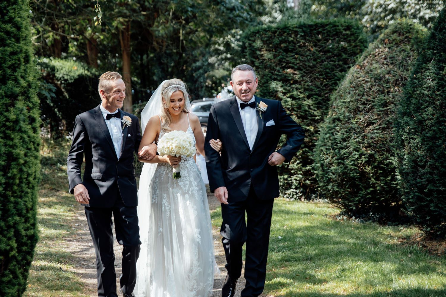 Wedding party walking together on a sunny garden path.