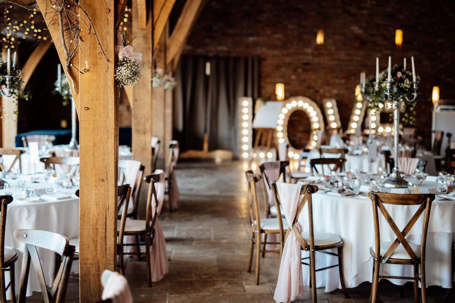 Rustic barn wedding reception setup with wooden beams and elegant table settings.