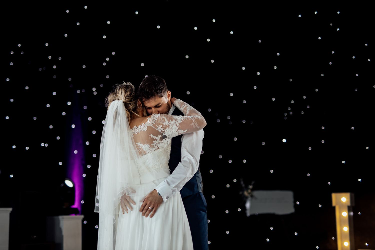 Couple sharing romantic first dance under twinkling lights.