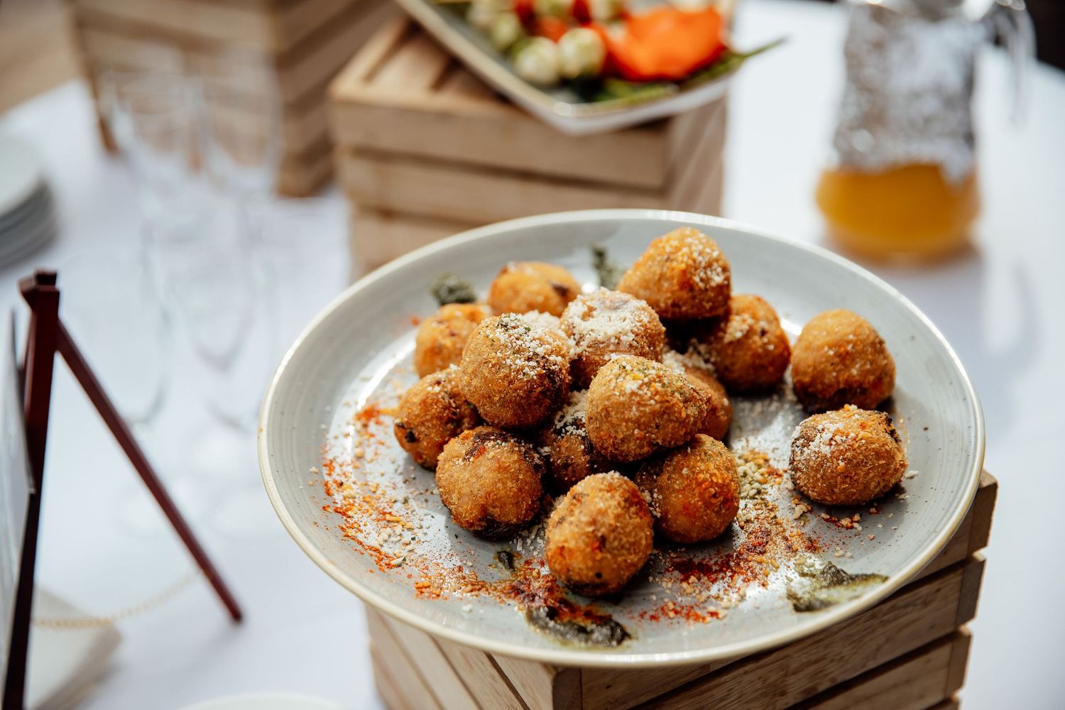 Plate of golden fried appetizer balls garnished with spices on white ceramic dish.