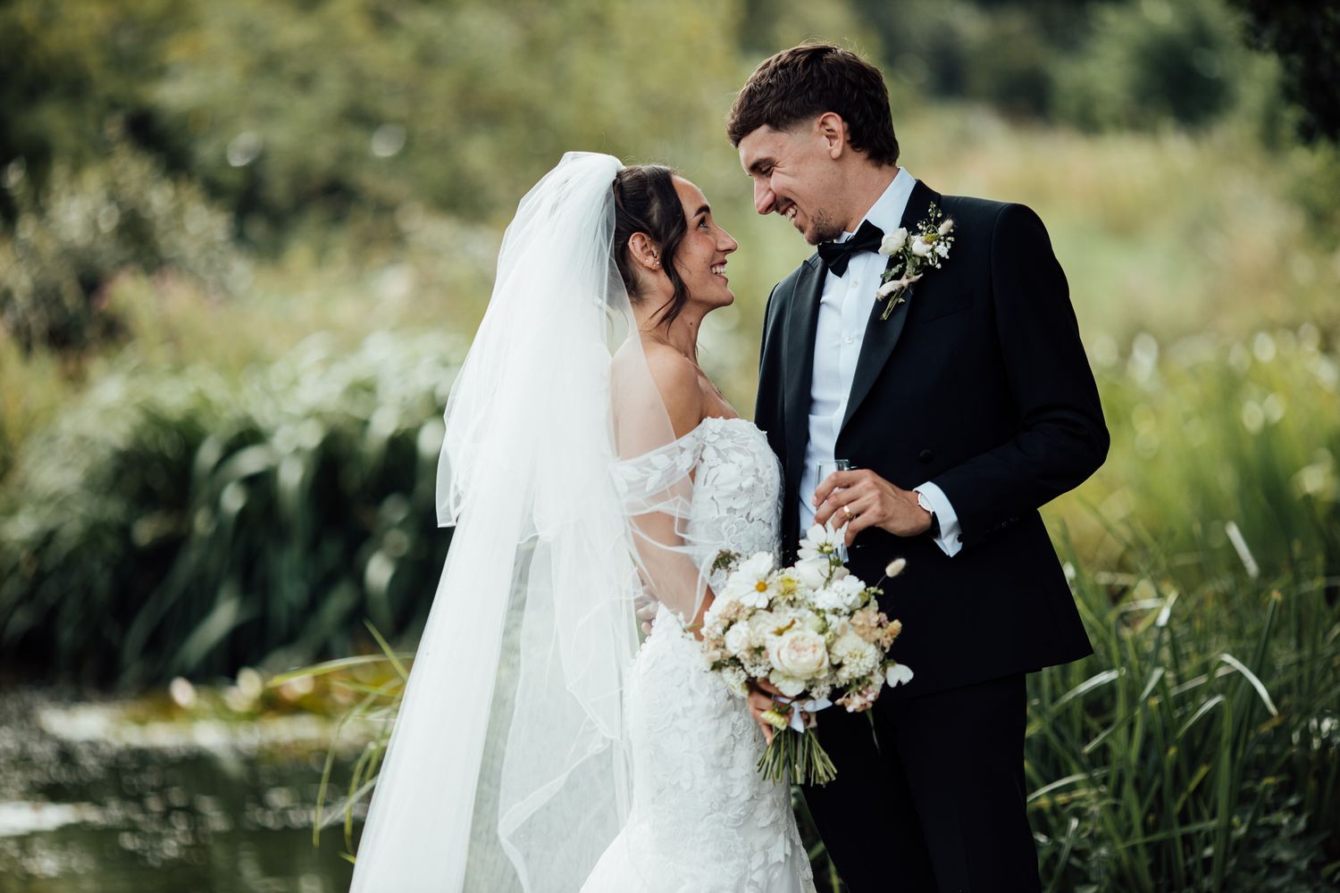 Romantic wedding portraits in natural outdoor setting with tall grass and sunlight.