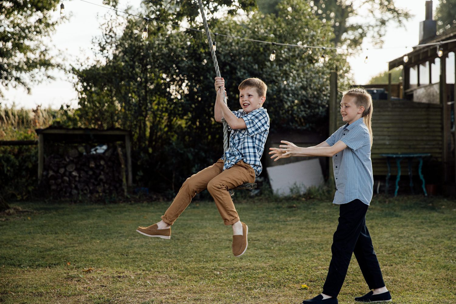 Children playing with a ball in a backyard garden setting during sunset.