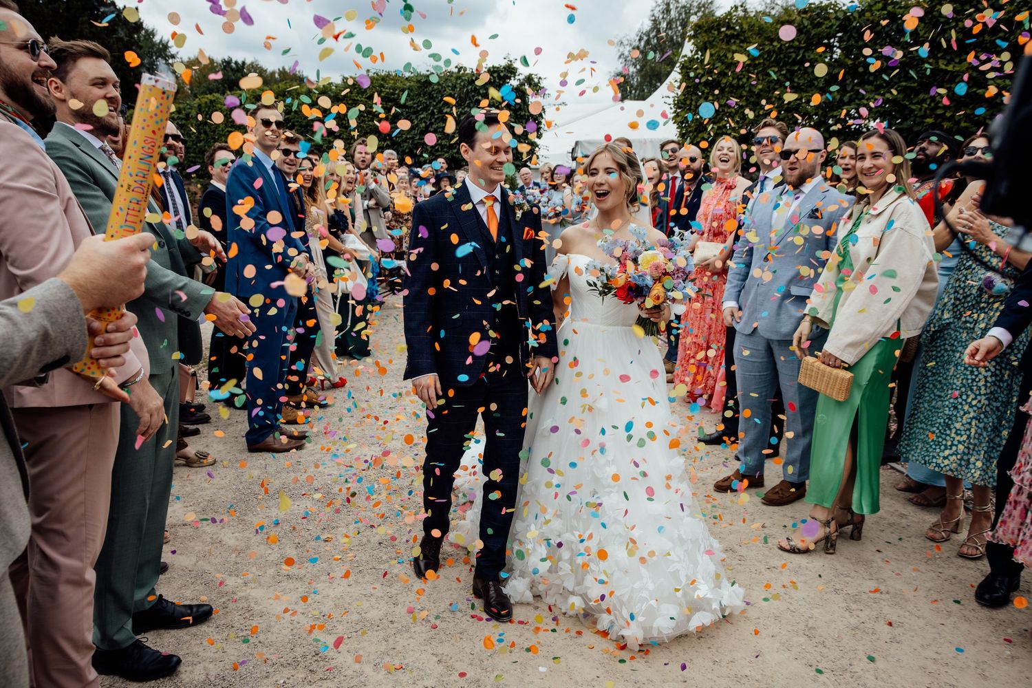 Wedding celebration with colorful confetti shower in an outdoor garden setting.