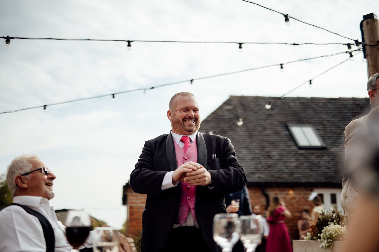 String lights hang overhead at an outdoor wedding venue creating a romantic atmosphere.