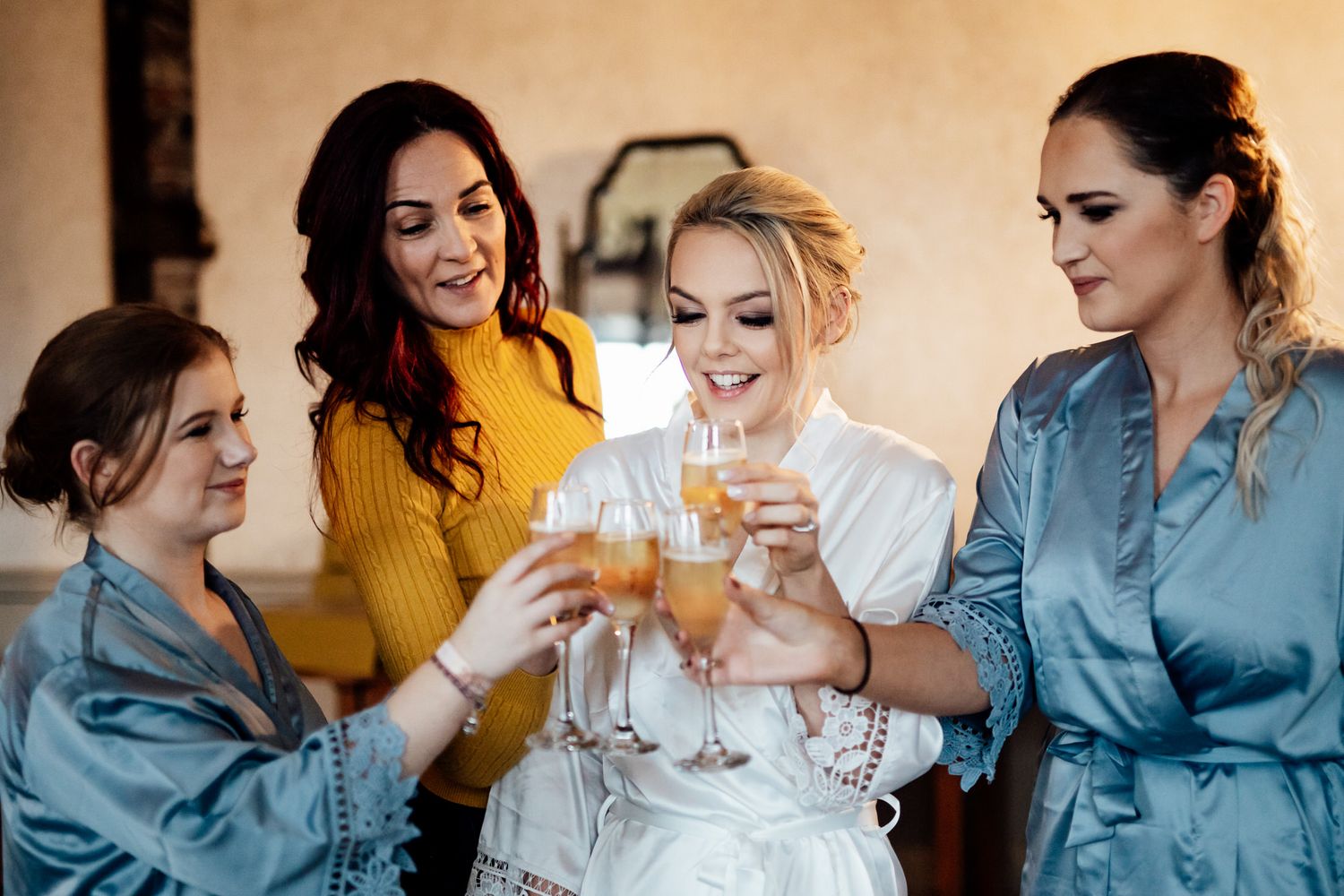 Wedding party in matching blue robes sharing champagne and laughter.