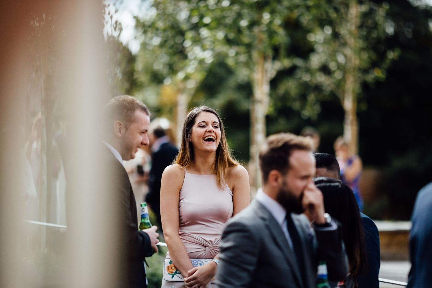 Outdoor wedding celebration with guests mingling in a garden setting.