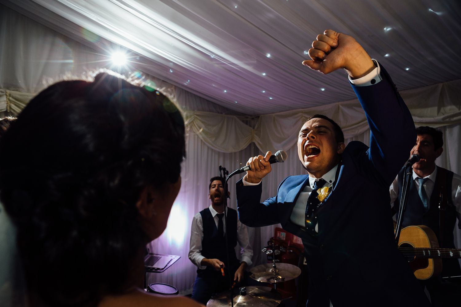 An energetic performance at a wedding reception with dramatic lighting.