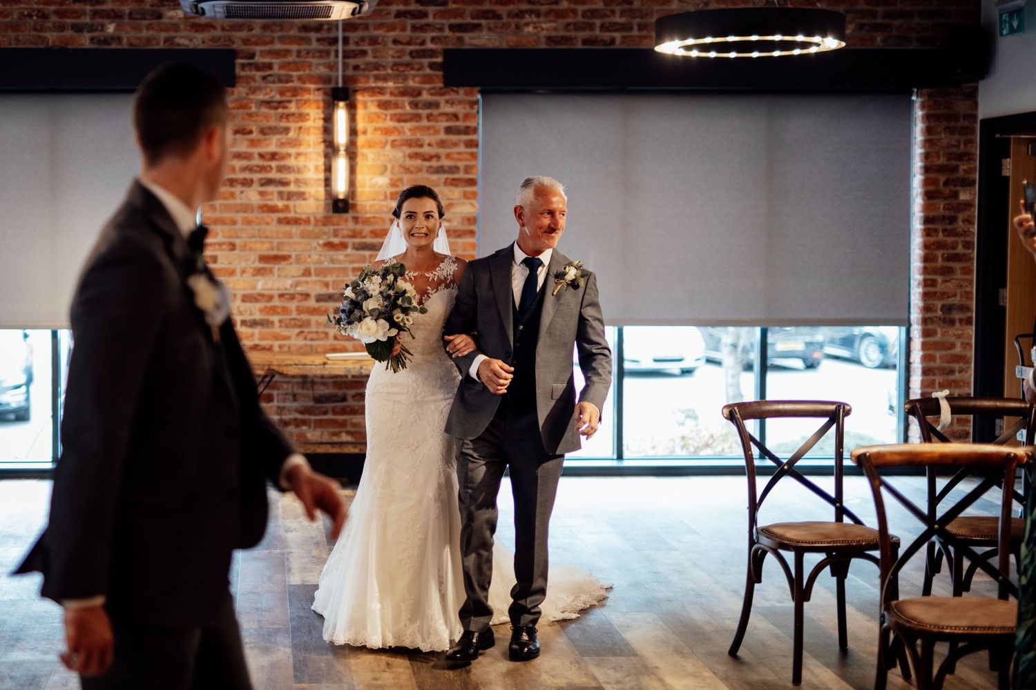Wedding ceremony in industrial chic venue with exposed brick walls and modern lighting.