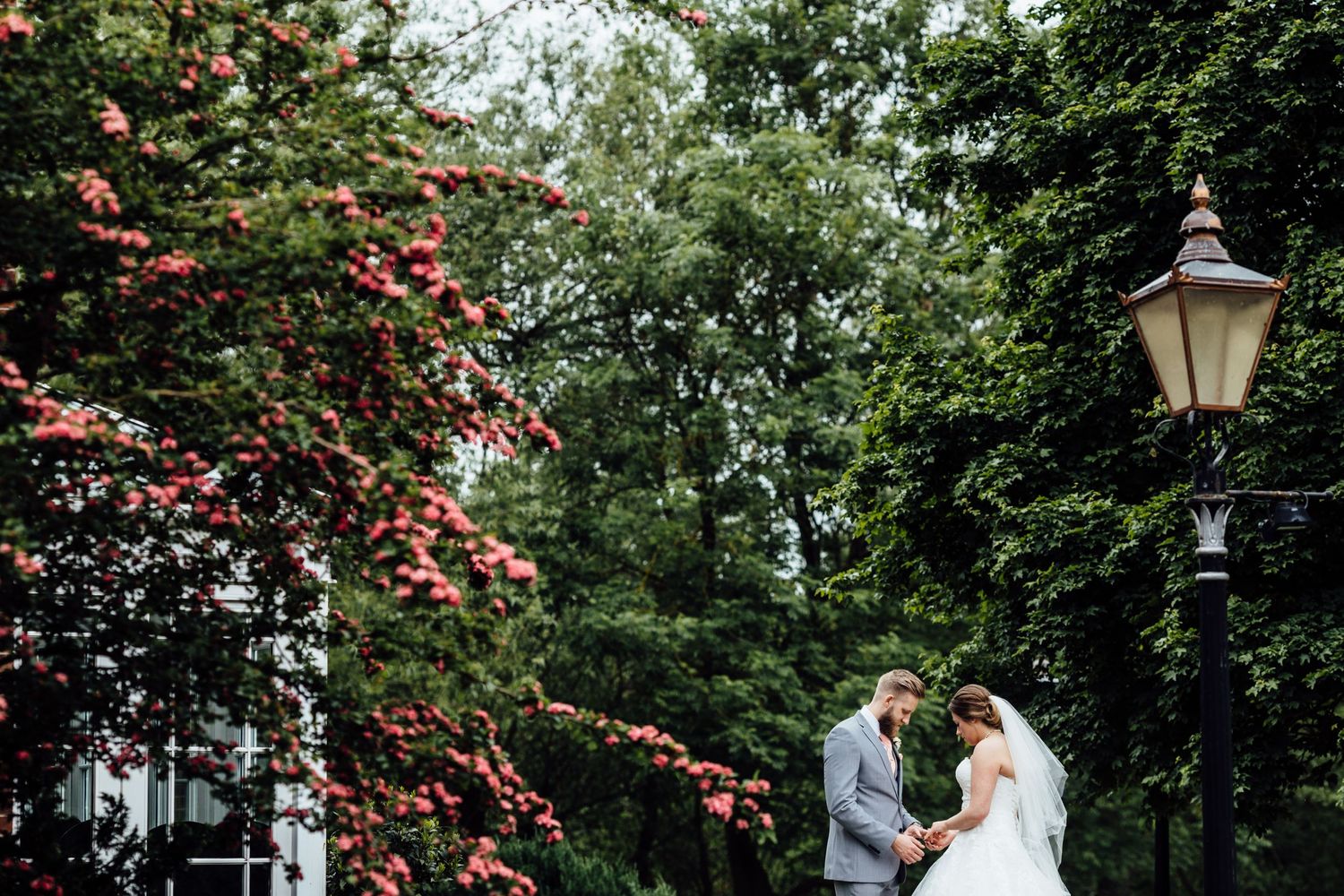 An elegant outdoor wedding ceremony setup with vintage lampposts and flowering trees.