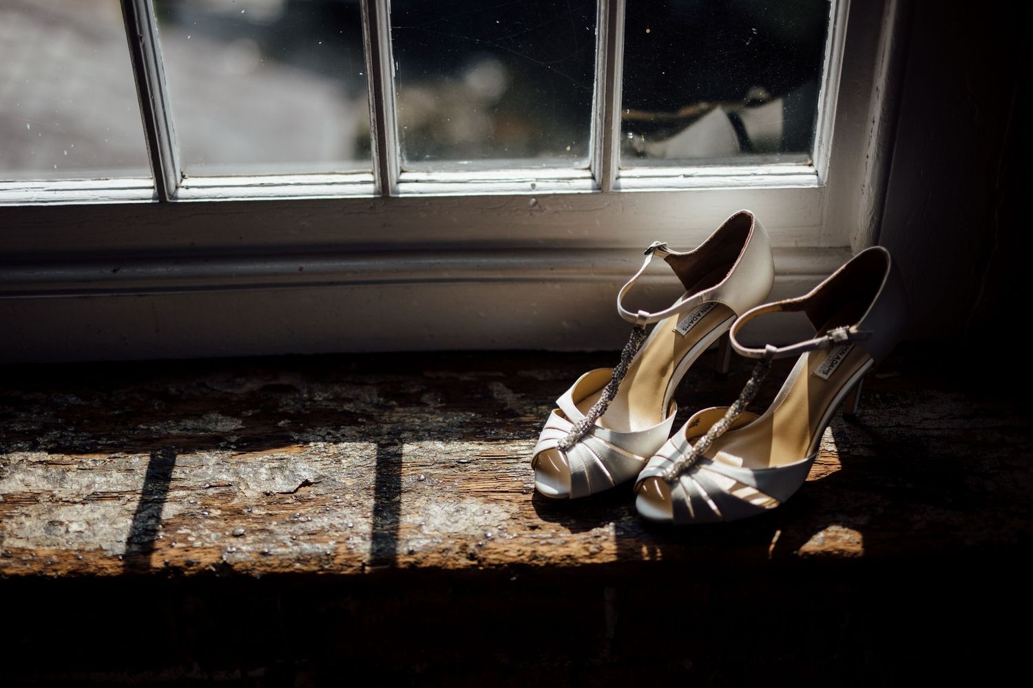 Elegant bridal shoes displayed near window with natural lighting.
