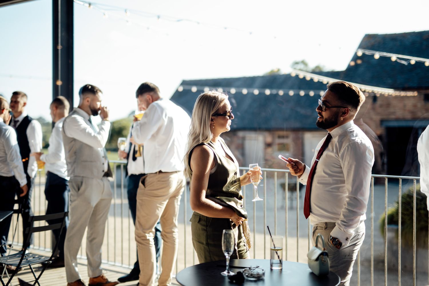 Guests mingling at an outdoor wedding reception with string lights overhead.