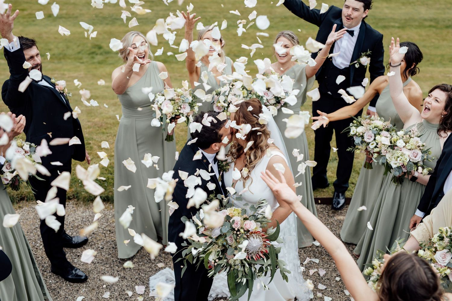 Wedding celebration with flower petals being thrown in the air as guests cheer.