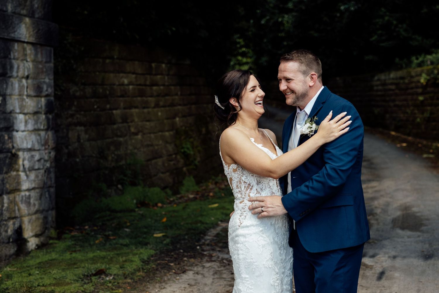 A couple shares romantic moments in a garden setting with stone architecture.