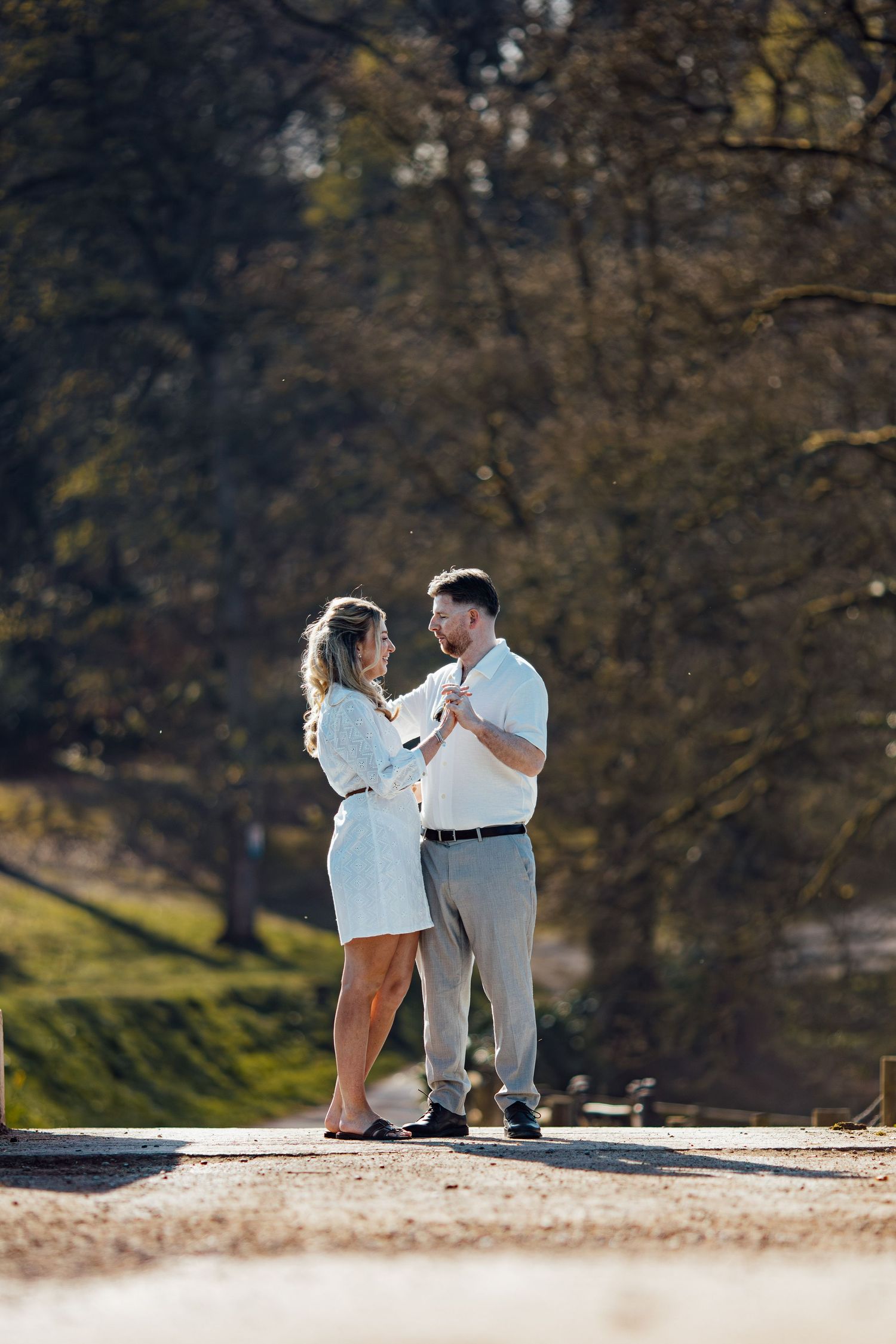 A couple shares a special moment on a sunlit path during their engagement session.