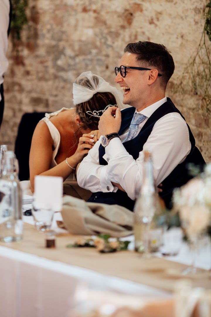 Wedding guests react with laughter during reception toasts and speeches.