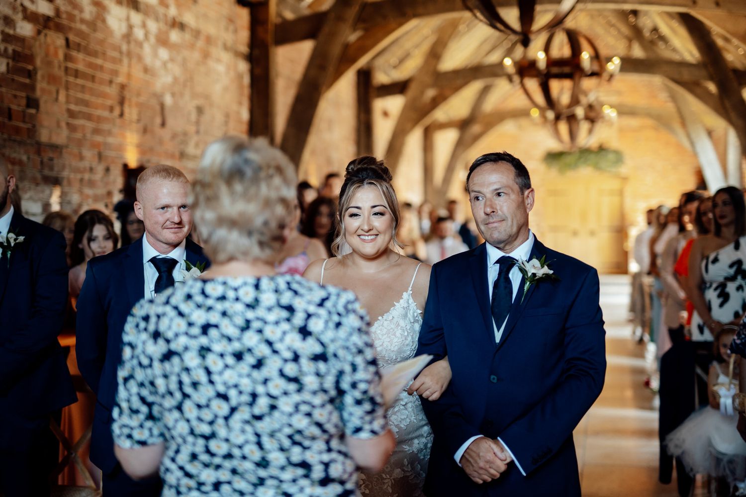 Wedding ceremony taking place in a rustic brick venue with wooden beams.
