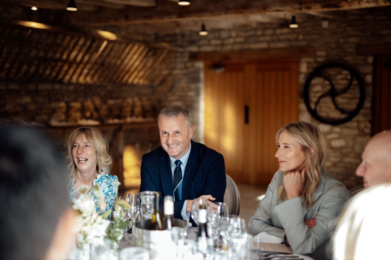 Wedding guests enjoying dinner and conversation at a rustic reception venue.