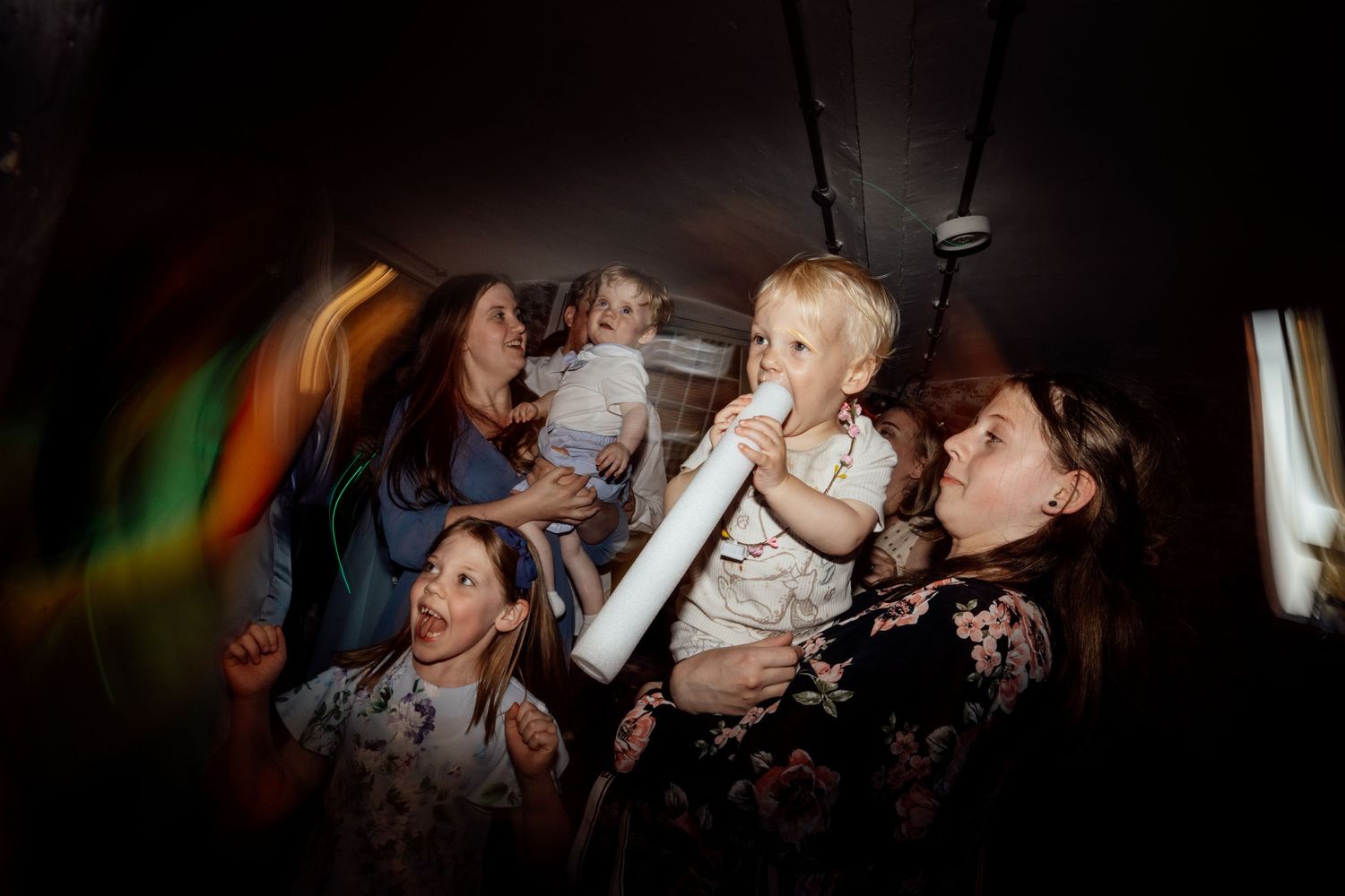 Lively dance floor moment at wedding reception with party lighting effects.