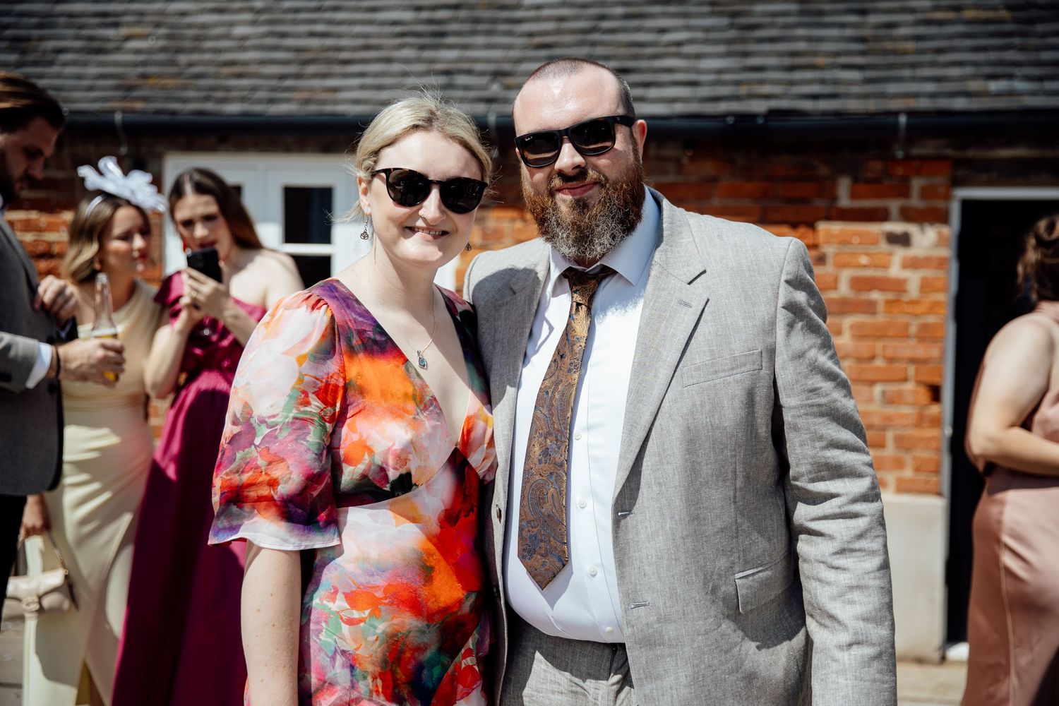 Wedding guests in colorful attire enjoying outdoor celebrations at brick venue.