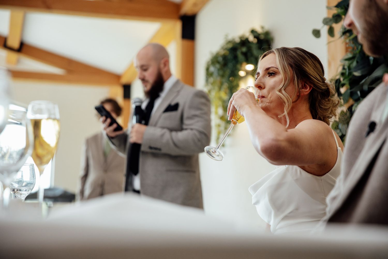 Wedding guests raise their glasses in a toast during an indoor reception.