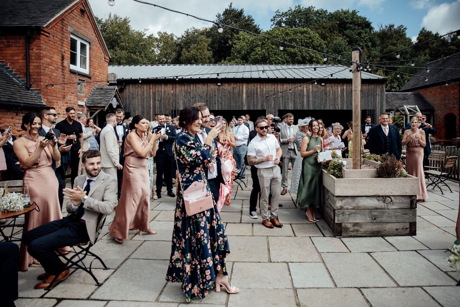 Guests mingle and socialize at an outdoor brick venue during a wedding reception.