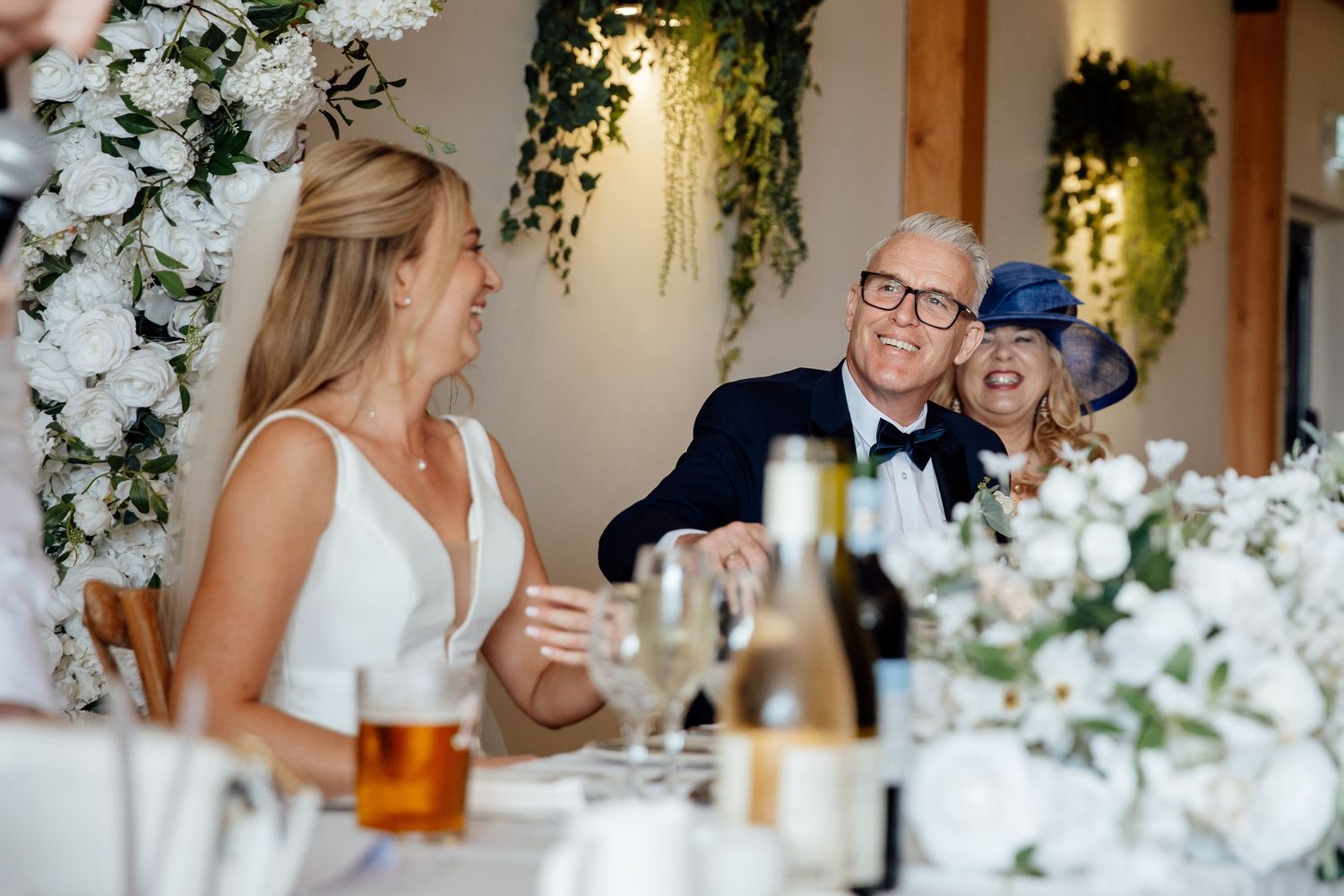 Wedding reception table decorated with elegant white floral arrangements and candlelight.