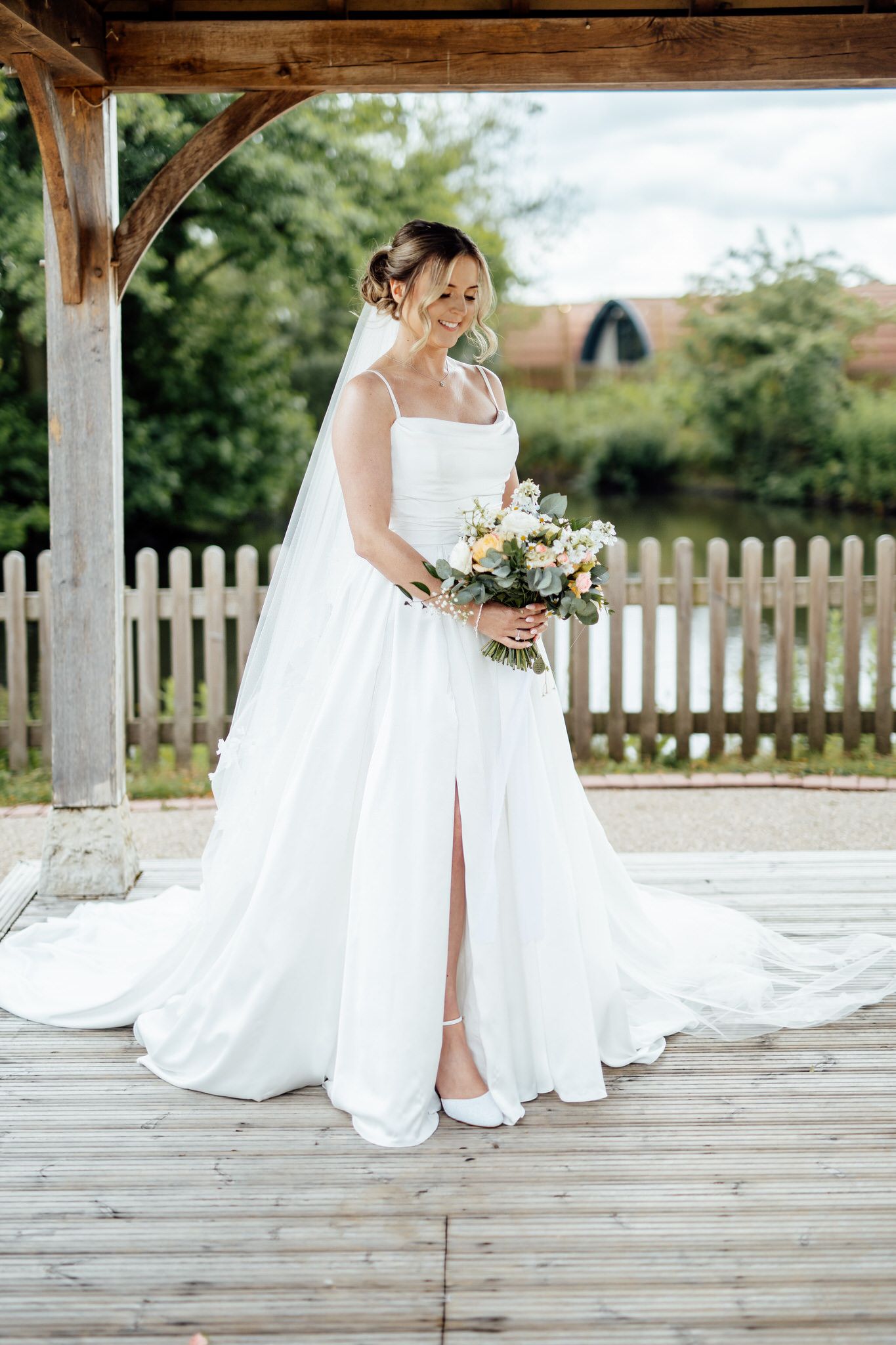 White wedding dress details on wooden deck with floral bouquet.