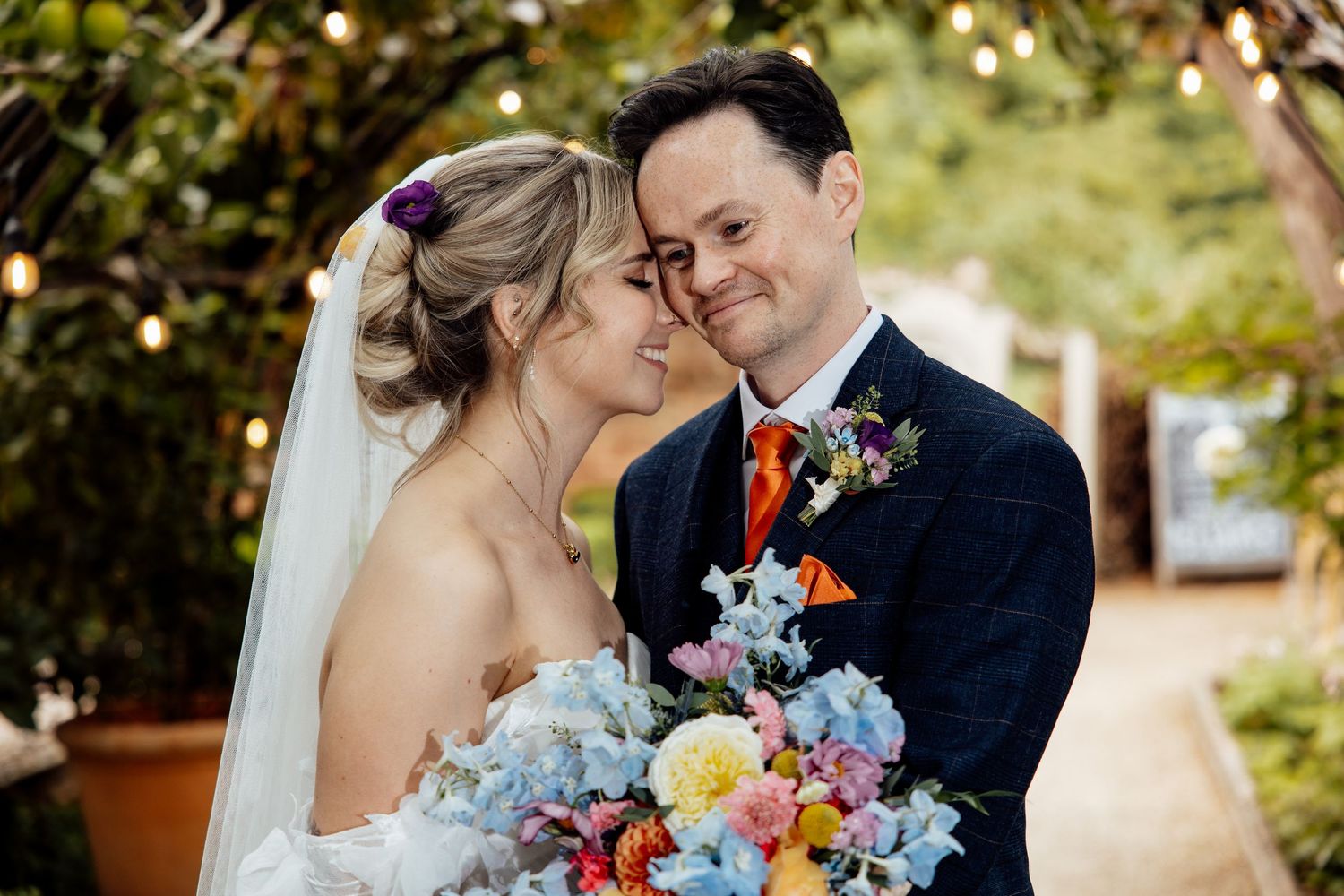 Intimate wedding moment captured in a lush garden setting with colorful bouquet.