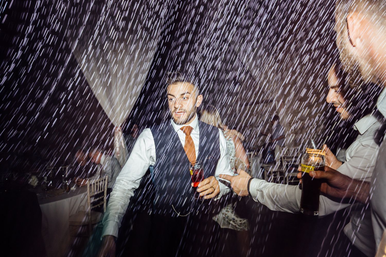 Wedding guests dancing under dramatic lighting with motion blur effects.