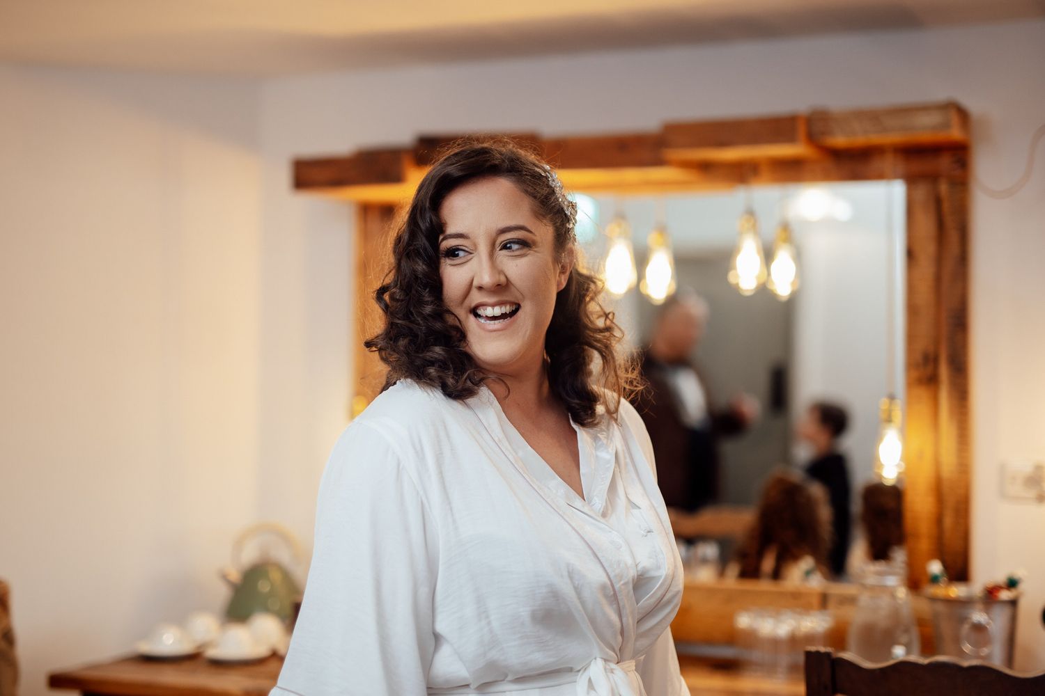 Getting ready moments in a bright room with natural window light and white robes.
