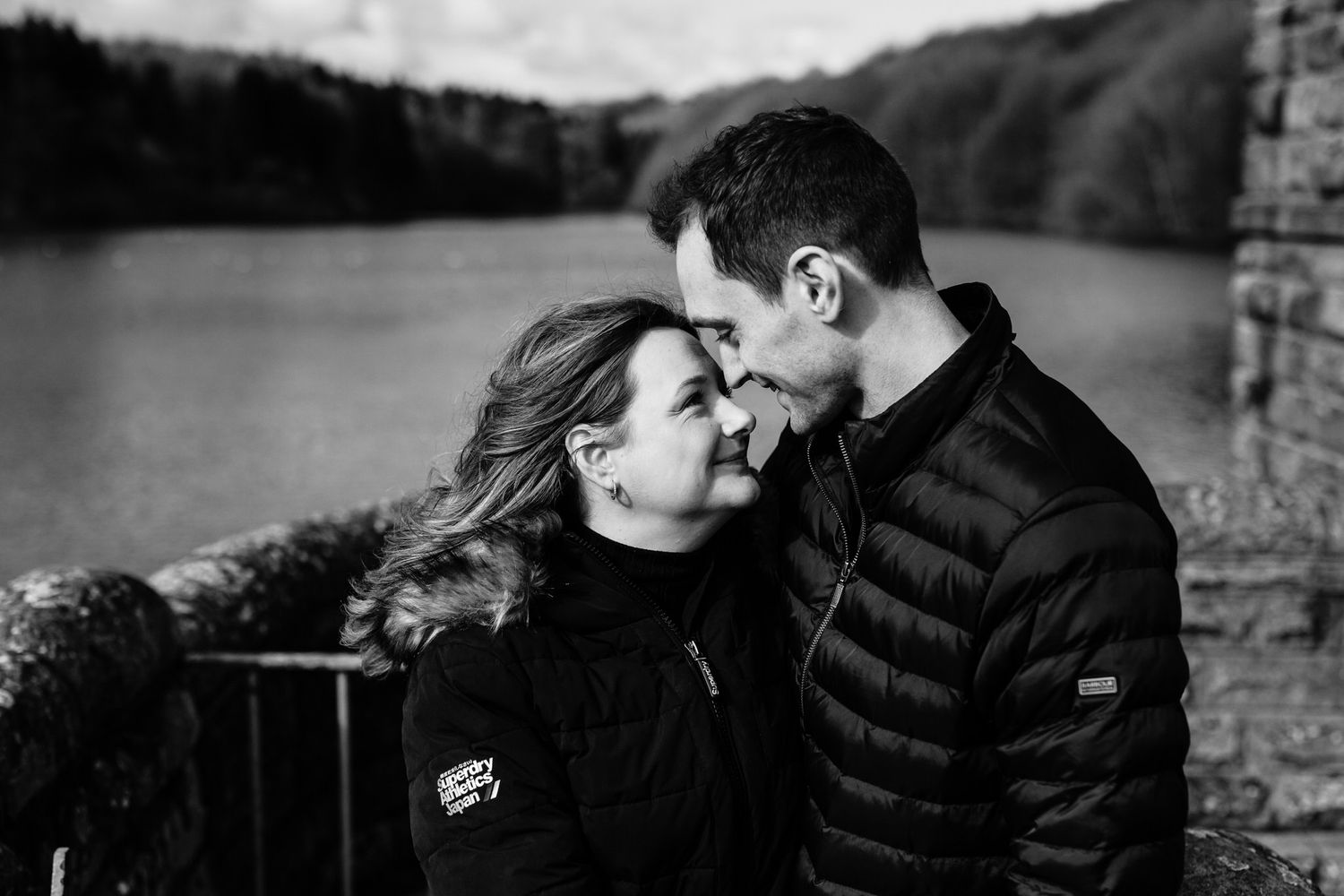 Intimate black and white portraits of couple against stone wall backdrop.