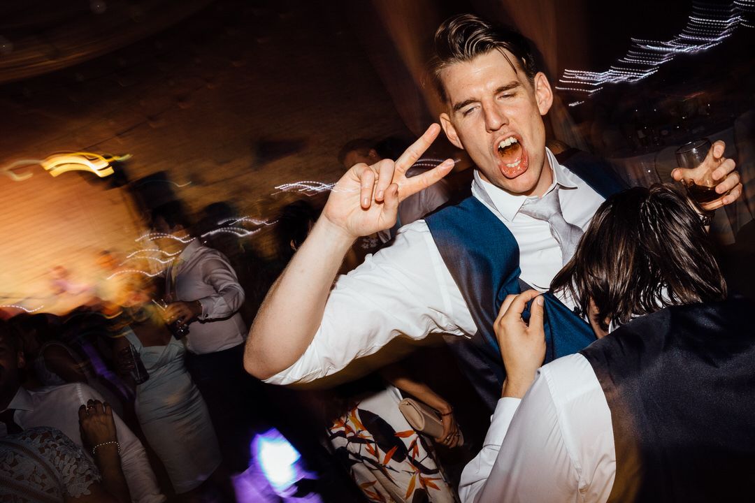 Energetic dance floor moments captured during wedding reception party.