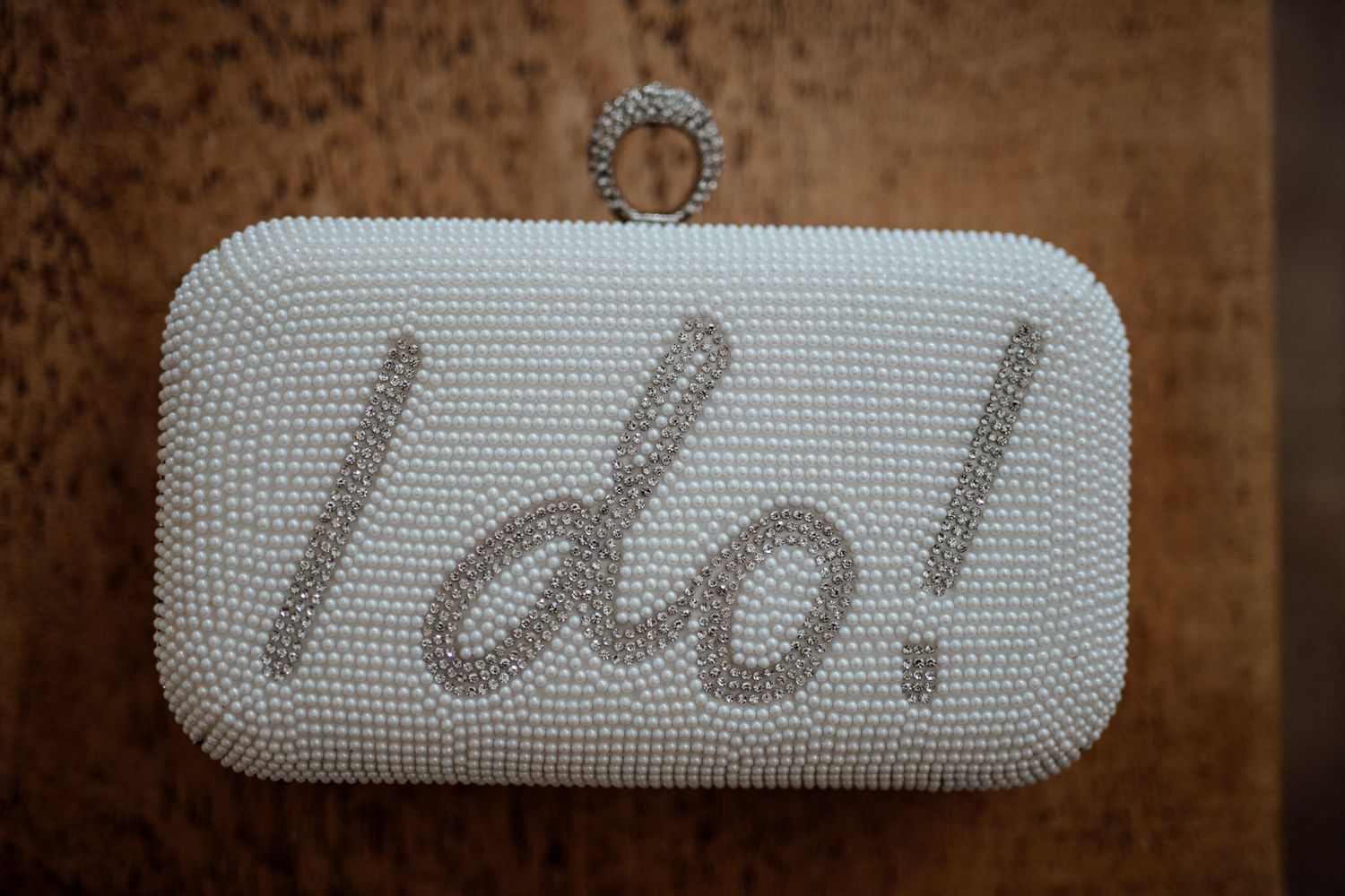 Pearl-studded wedding accessories arranged artistically on brown textured background.
