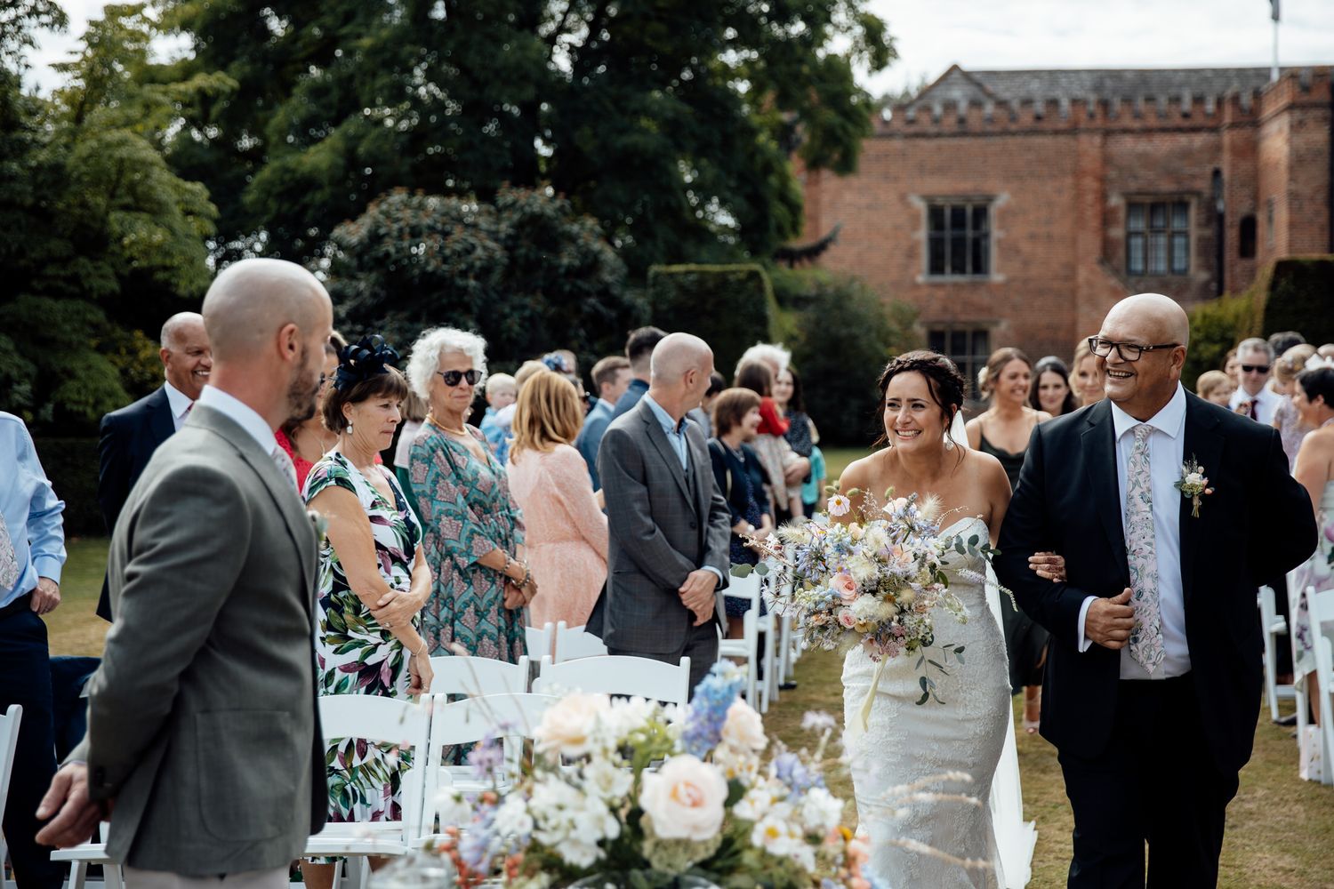 Wedding reception tables set outdoors with floral centerpieces and white decor.