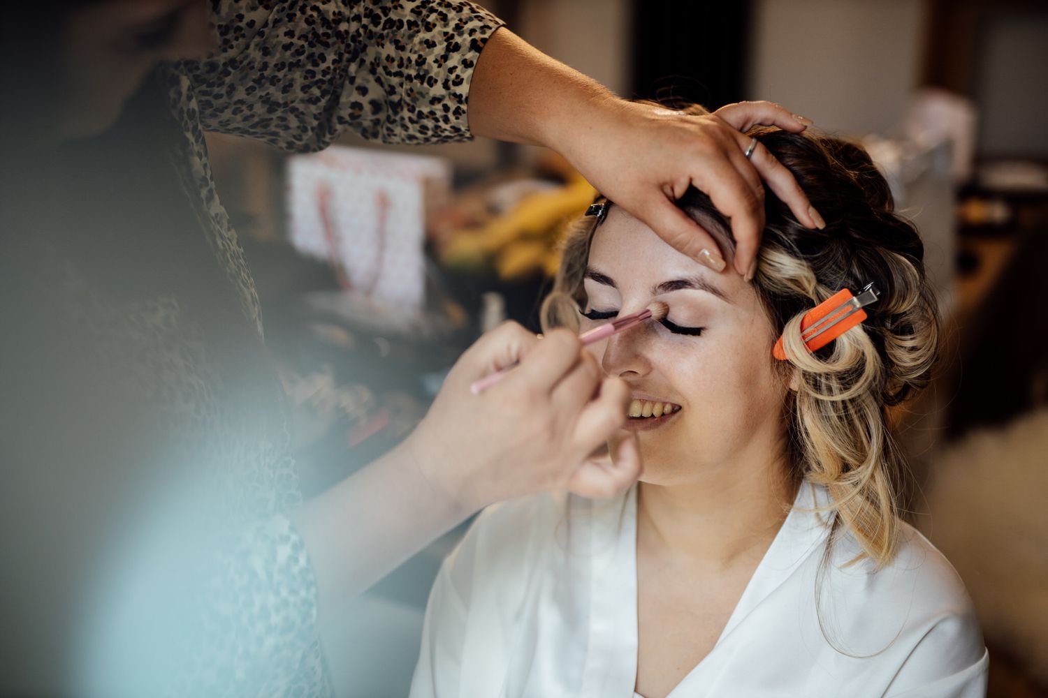 Candid moments of wedding day makeup application in natural light.