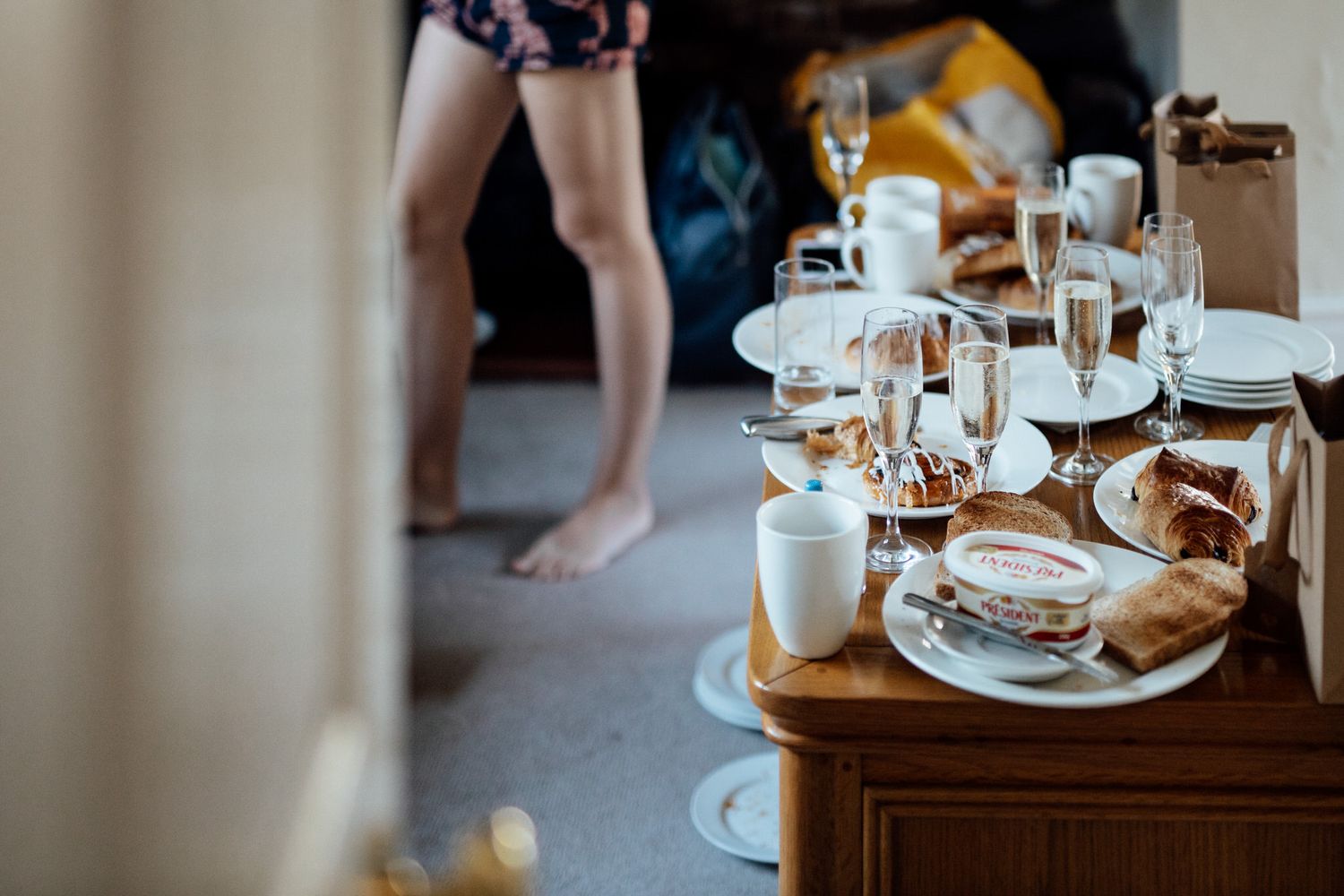 Wedding morning preparation details with coffee and breakfast items on rustic wooden table.