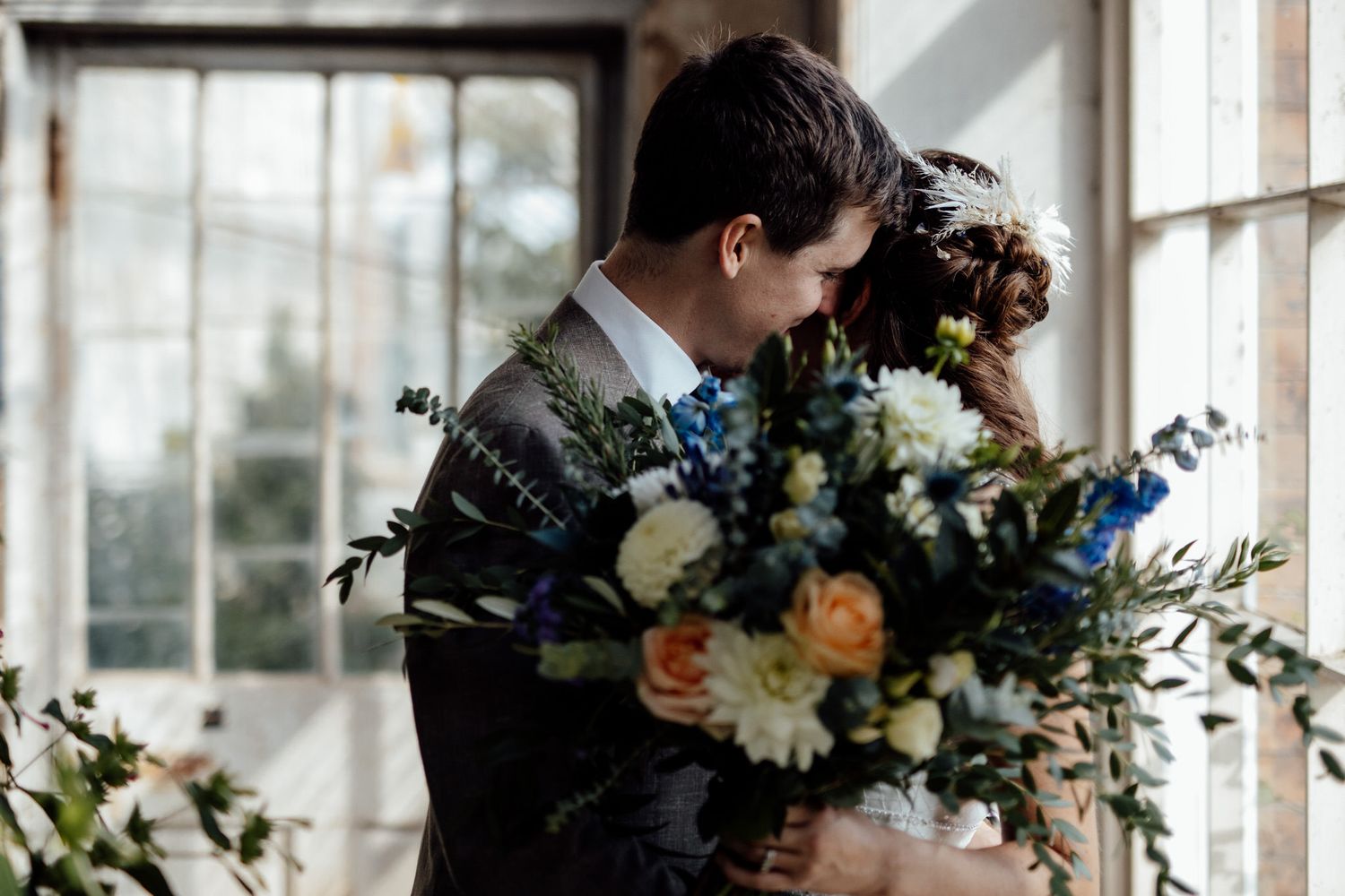 Elegant indoor wedding ceremony with natural light streaming through windows and floral arrangements.