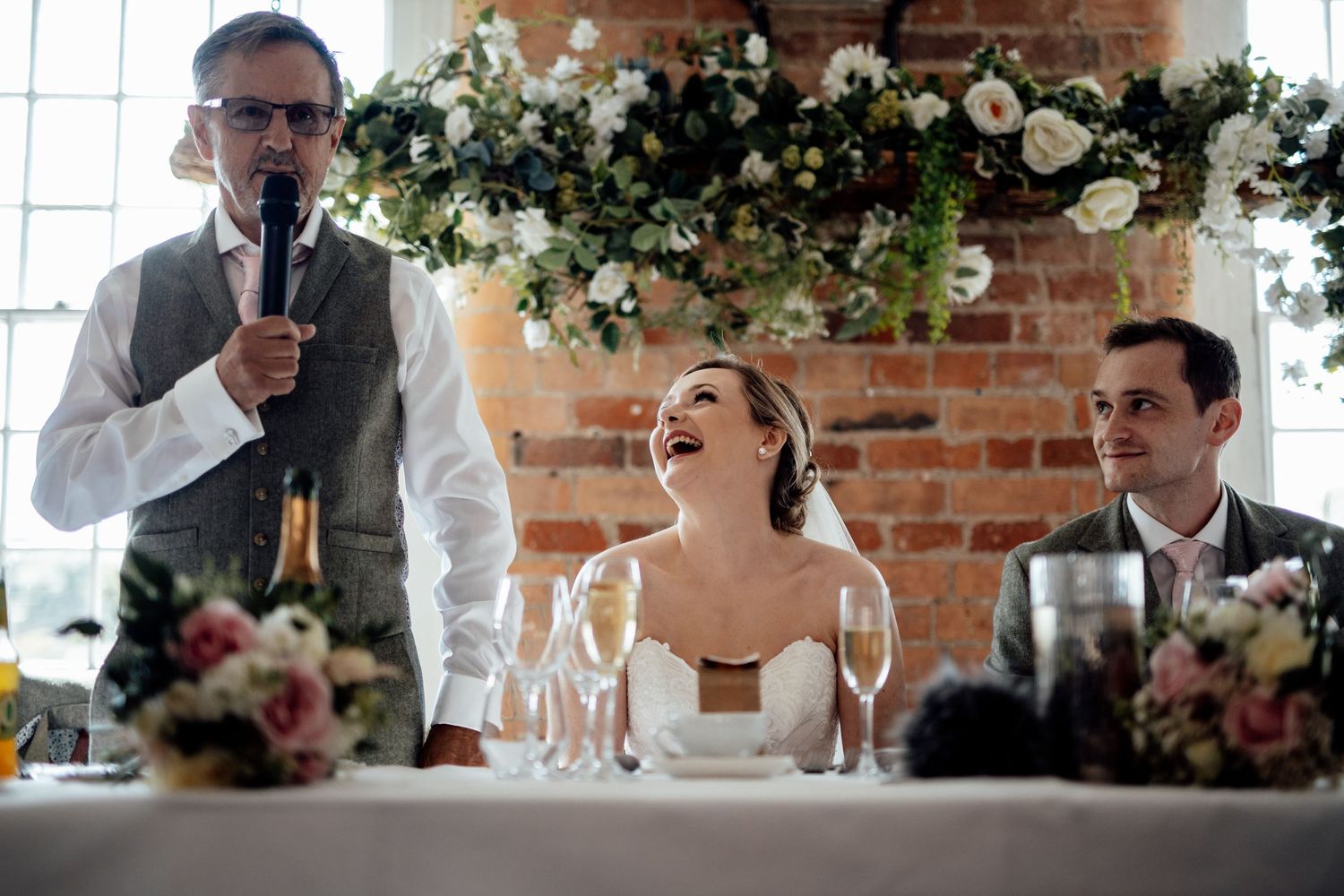 Wedding reception setup with floral decorations and exposed brick interior.