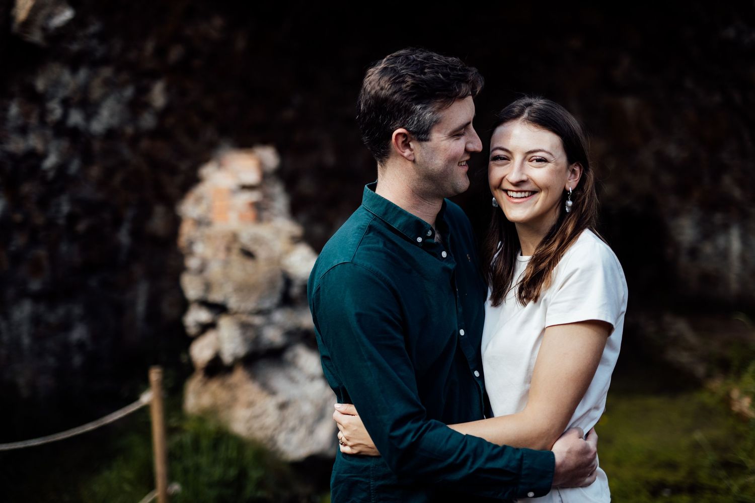 Intimate portrait session in moody lighting against stone wall backdrop.