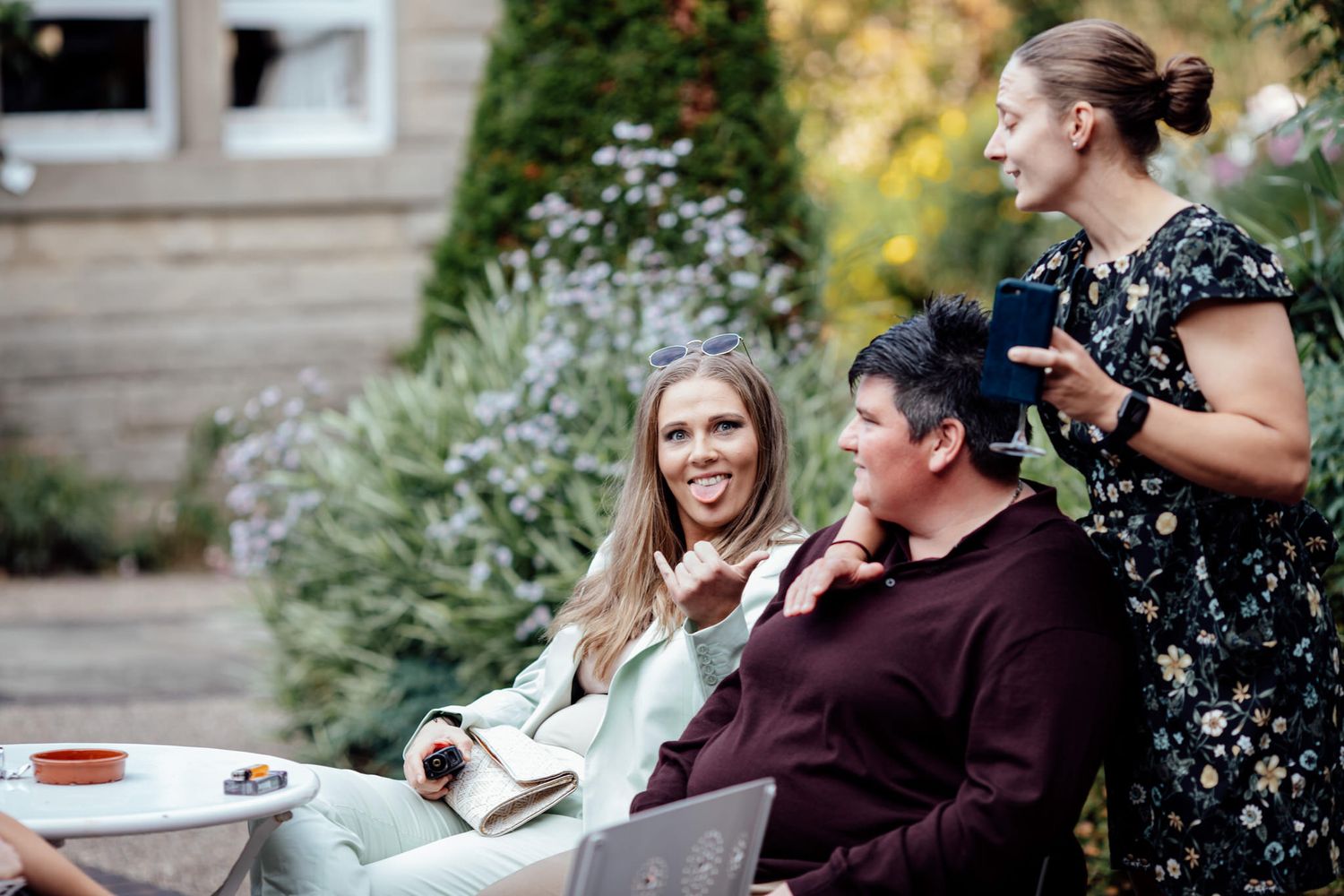 Outdoor wedding gathering with guests relaxing on rustic wooden furniture.