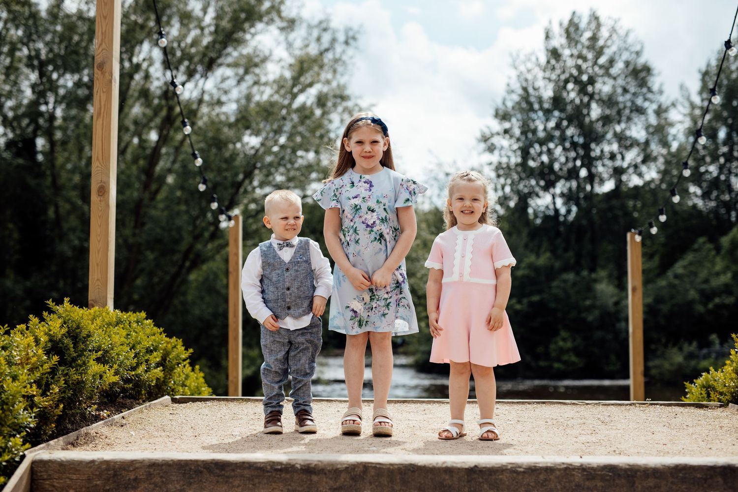 Children's feet in formal shoes lined up on a stone path outdoors.