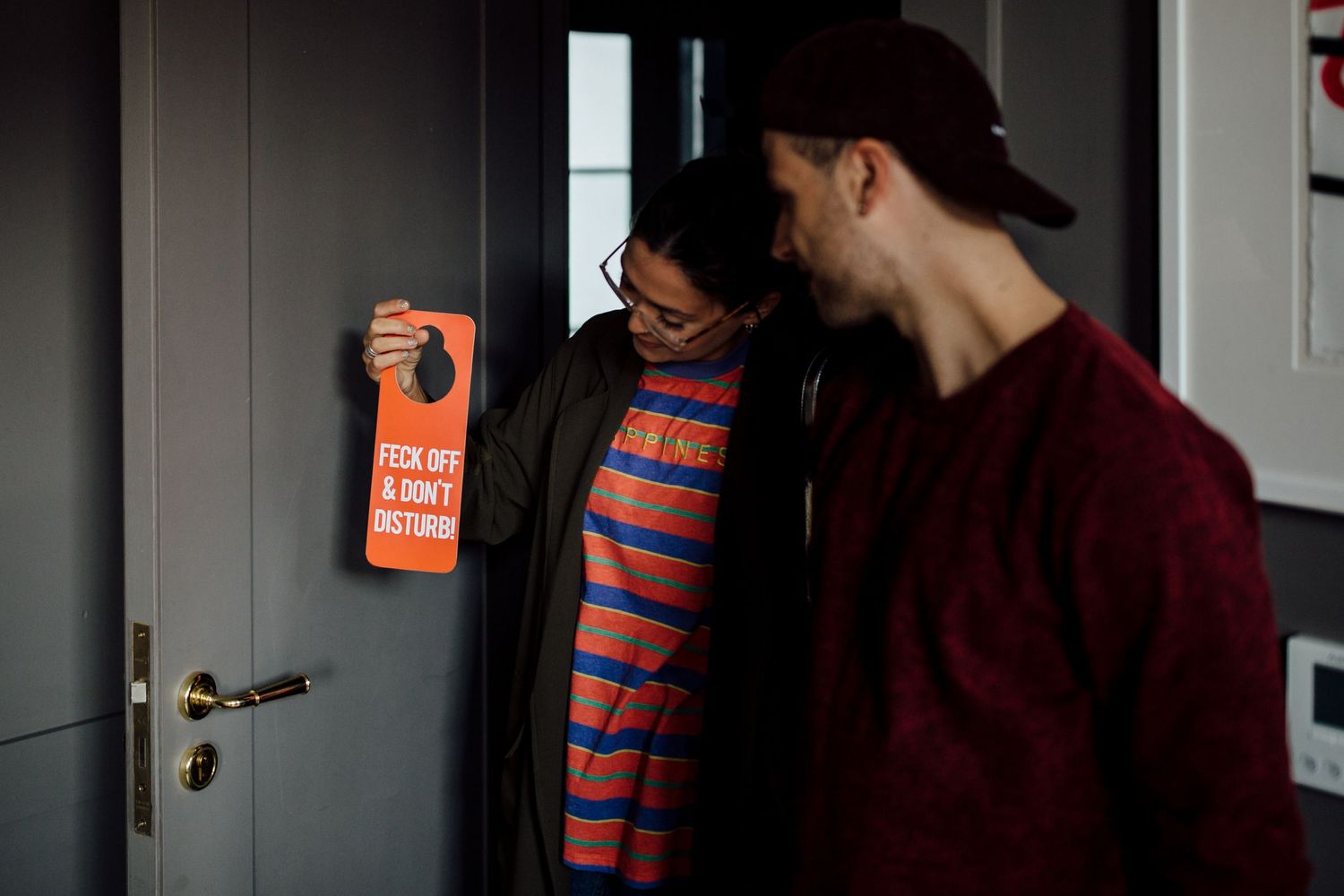 Two people conversing in a bright indoor hallway setting.