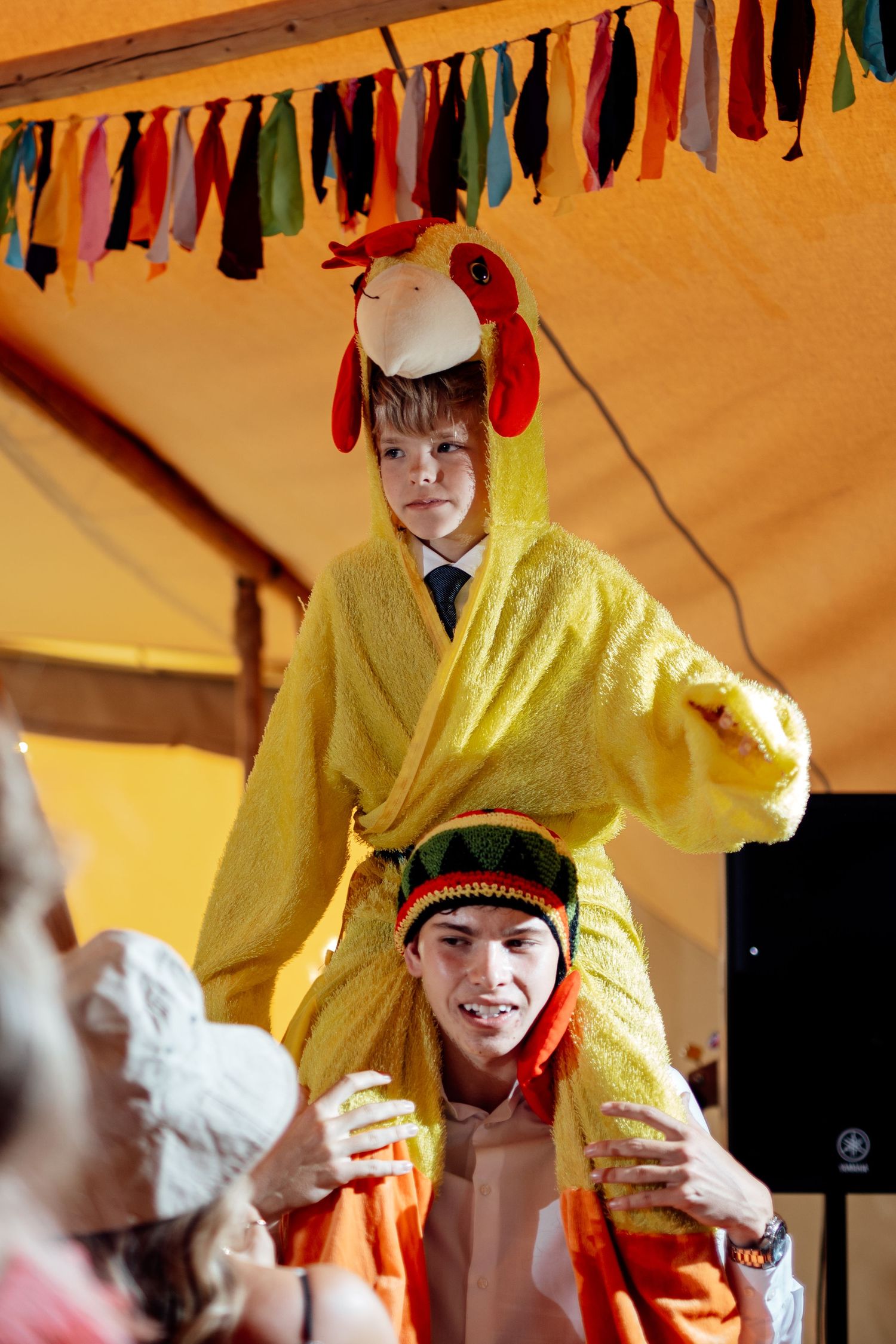 Festive celebration under colorful bunting decorations in a yellow-lit tent.