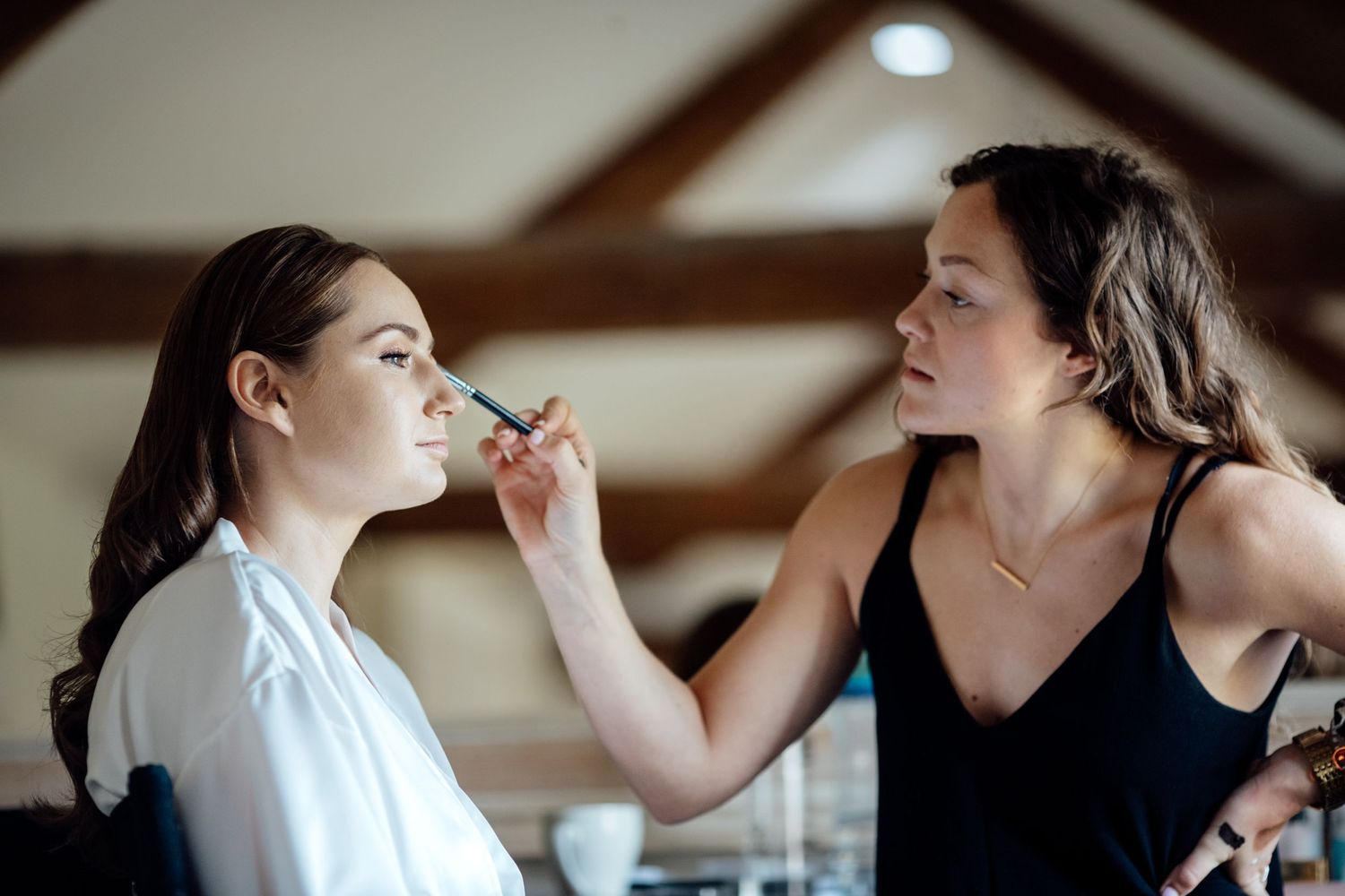 Wedding party members getting hair and makeup done during preparation.