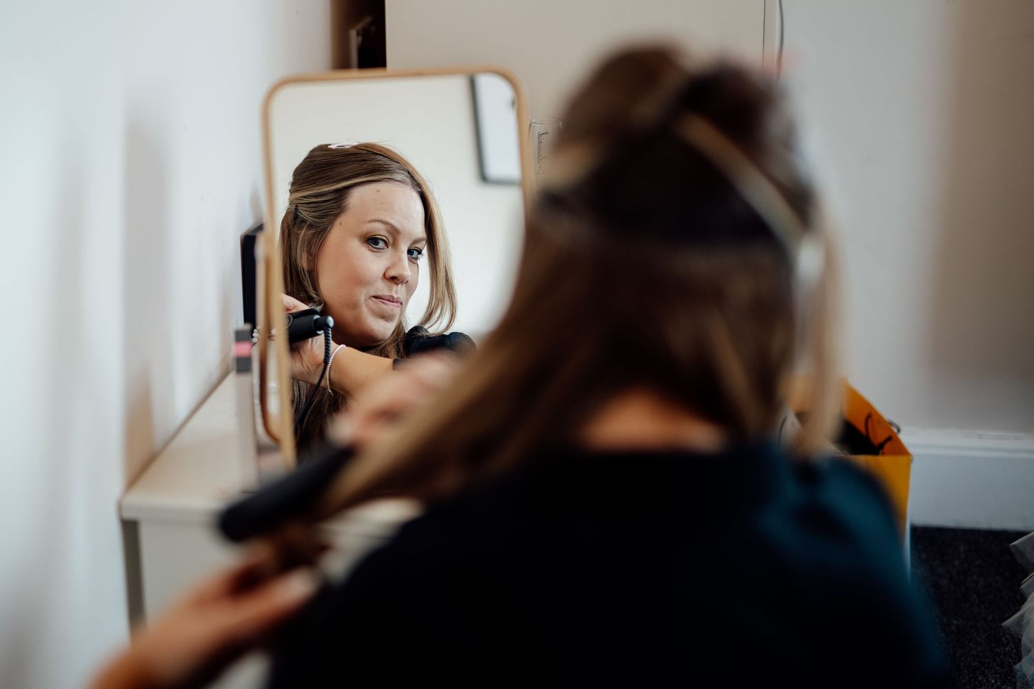Preparation scene with hair styling reflected in a mirror before the wedding ceremony.
