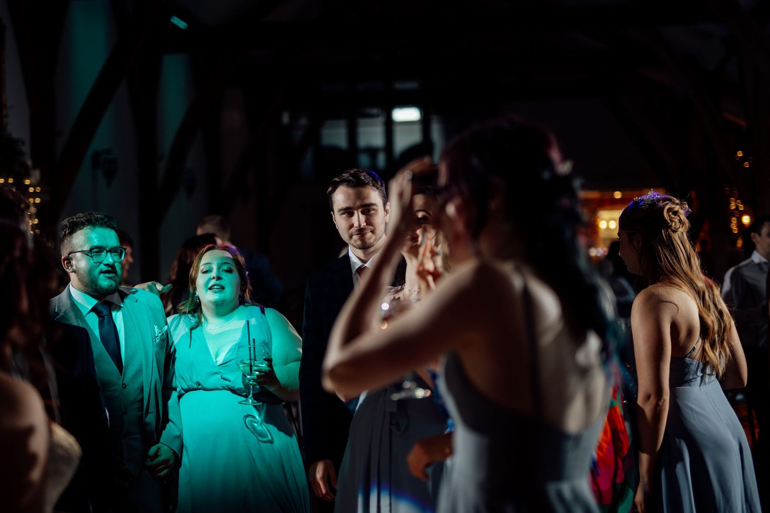 Wedding reception dance floor with colorful lighting and dancing guests in evening atmosphere.