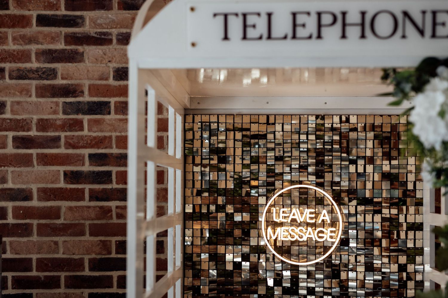 Vintage telephone sign mounted on rustic brick wall with decorative lighting.