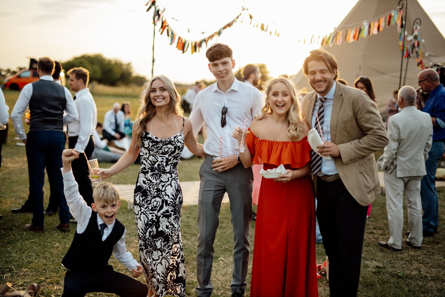 Wedding guests dancing and mingling outdoors during golden hour celebration.