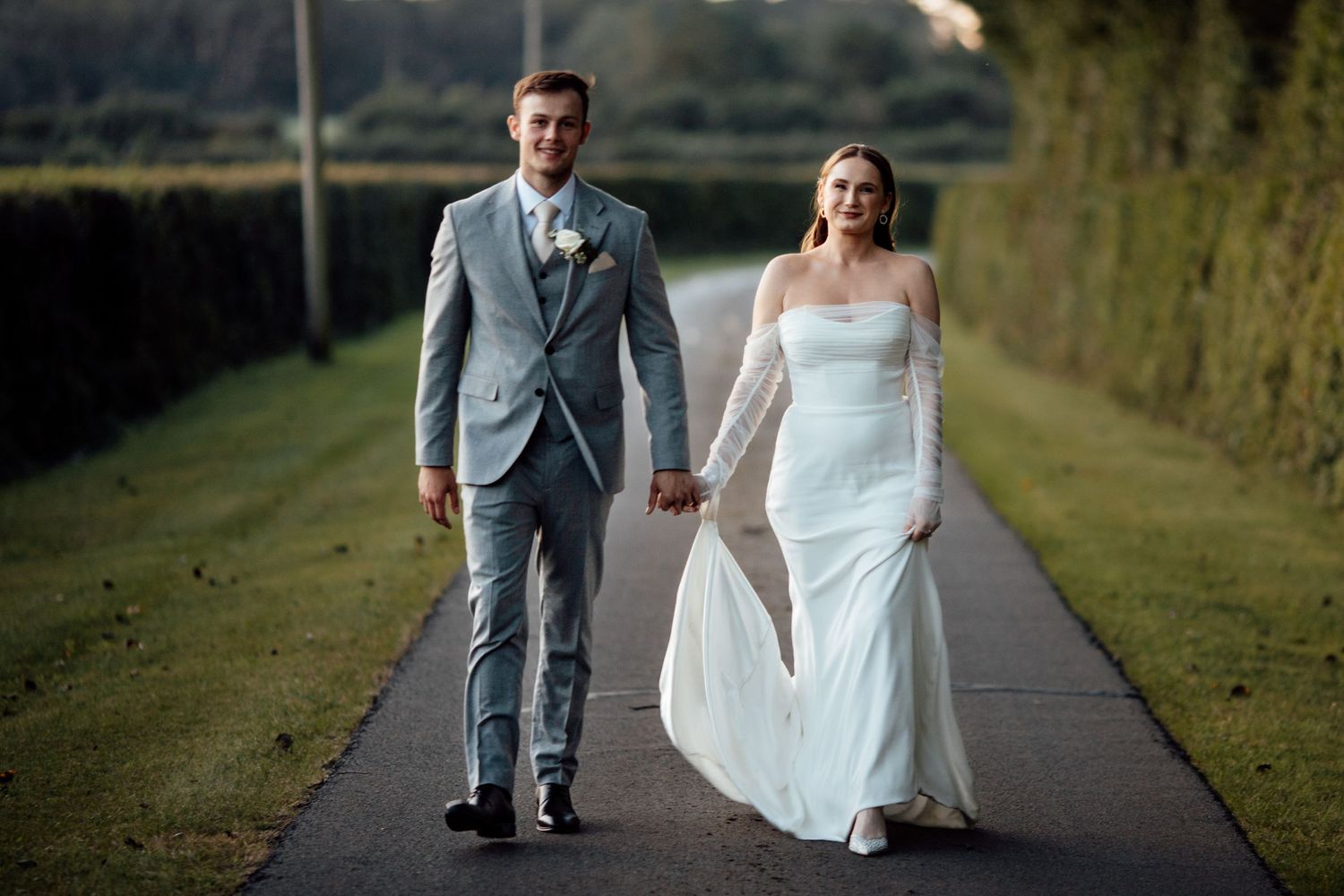 Newlyweds walking together on a countryside path during golden hour.