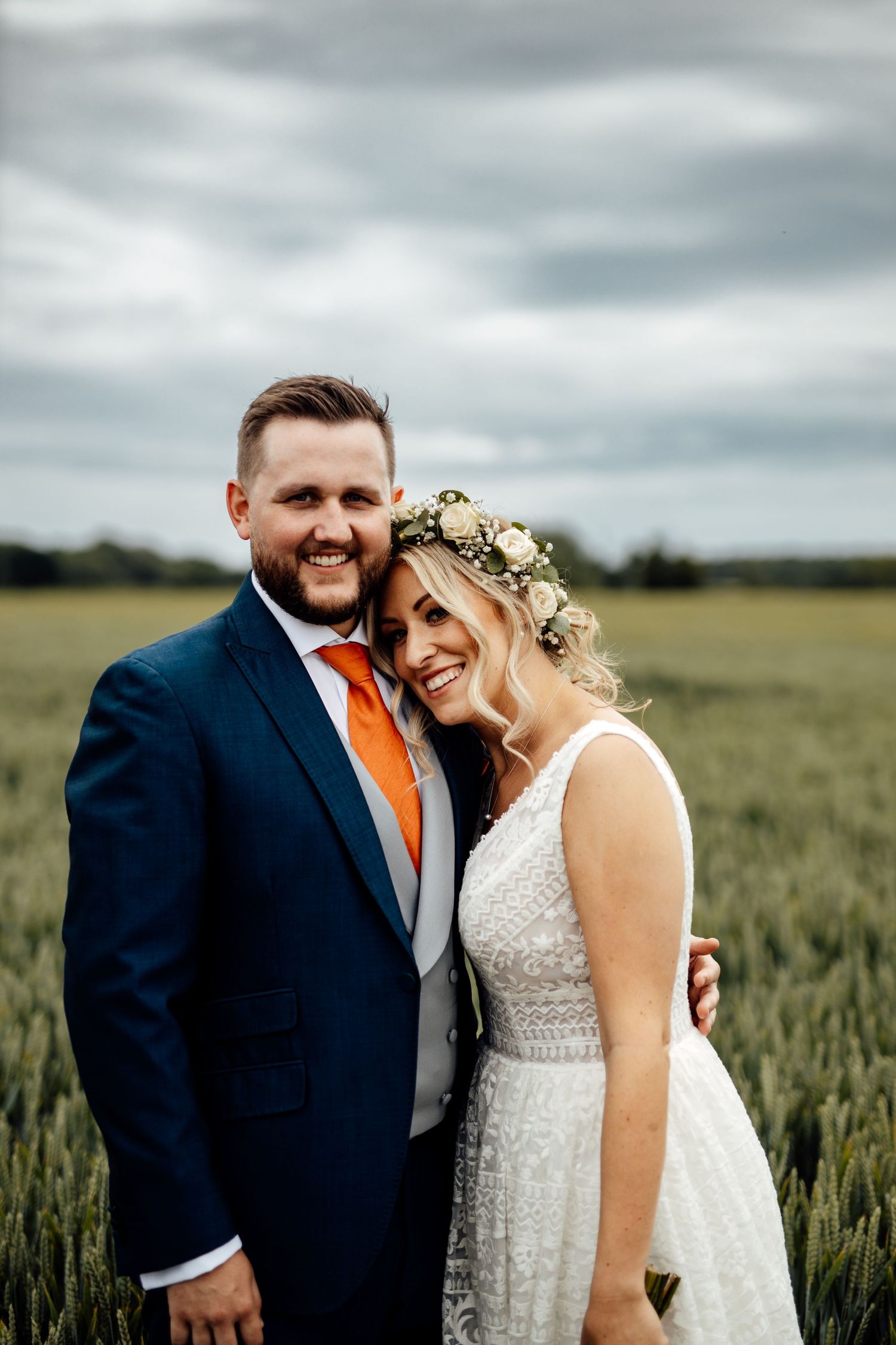 Romantic wedding portraits taken in a wheat field under cloudy skies.
